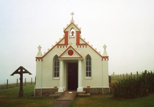Veduta dell’Italian Chapel di Lamb Holm. Il Crocefisso in legno a sinistra dell’edificio fu donato dal Comune di Moena nel 1961