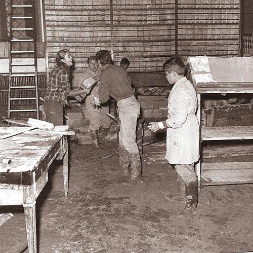 Dopo l'esondazione dell'Arno del 4 novembre 1966, giunsero a Firenze giovani volontari da tutto il mondo per offrire un concreto aiuto e vennero chiamati 'Angeli del fango'. Qui vediamo alcuni di loro al lavora all’Archivio di Stato di Firenze. 